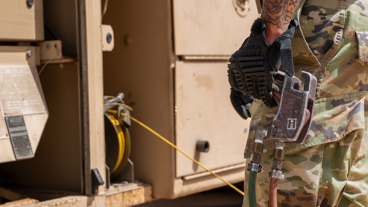 A close shot of a hand holding a lever connected to a fuel truck.
