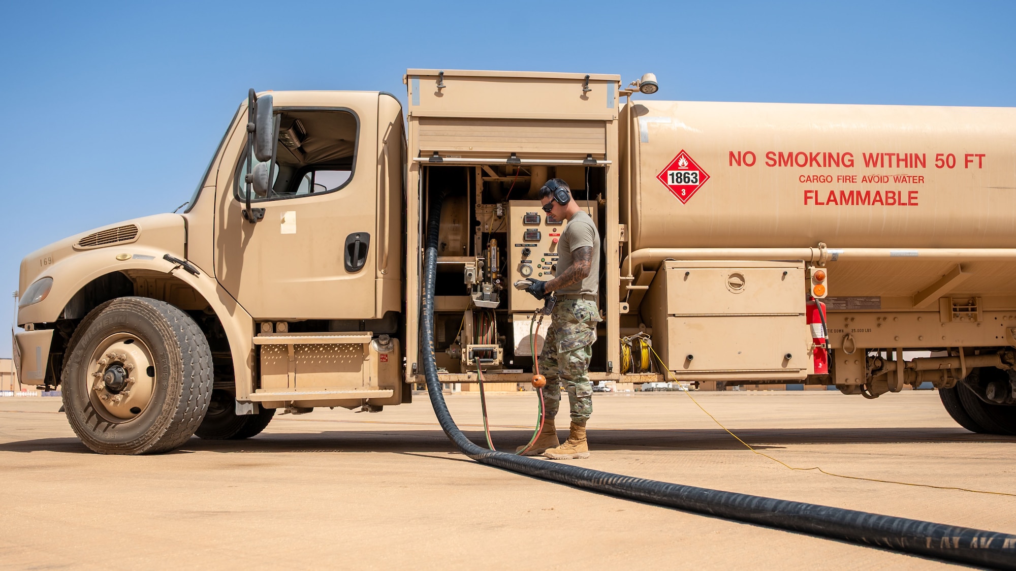 A man read a technical order beside a fuel truck.