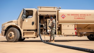 A man read a technical order beside a fuel truck.