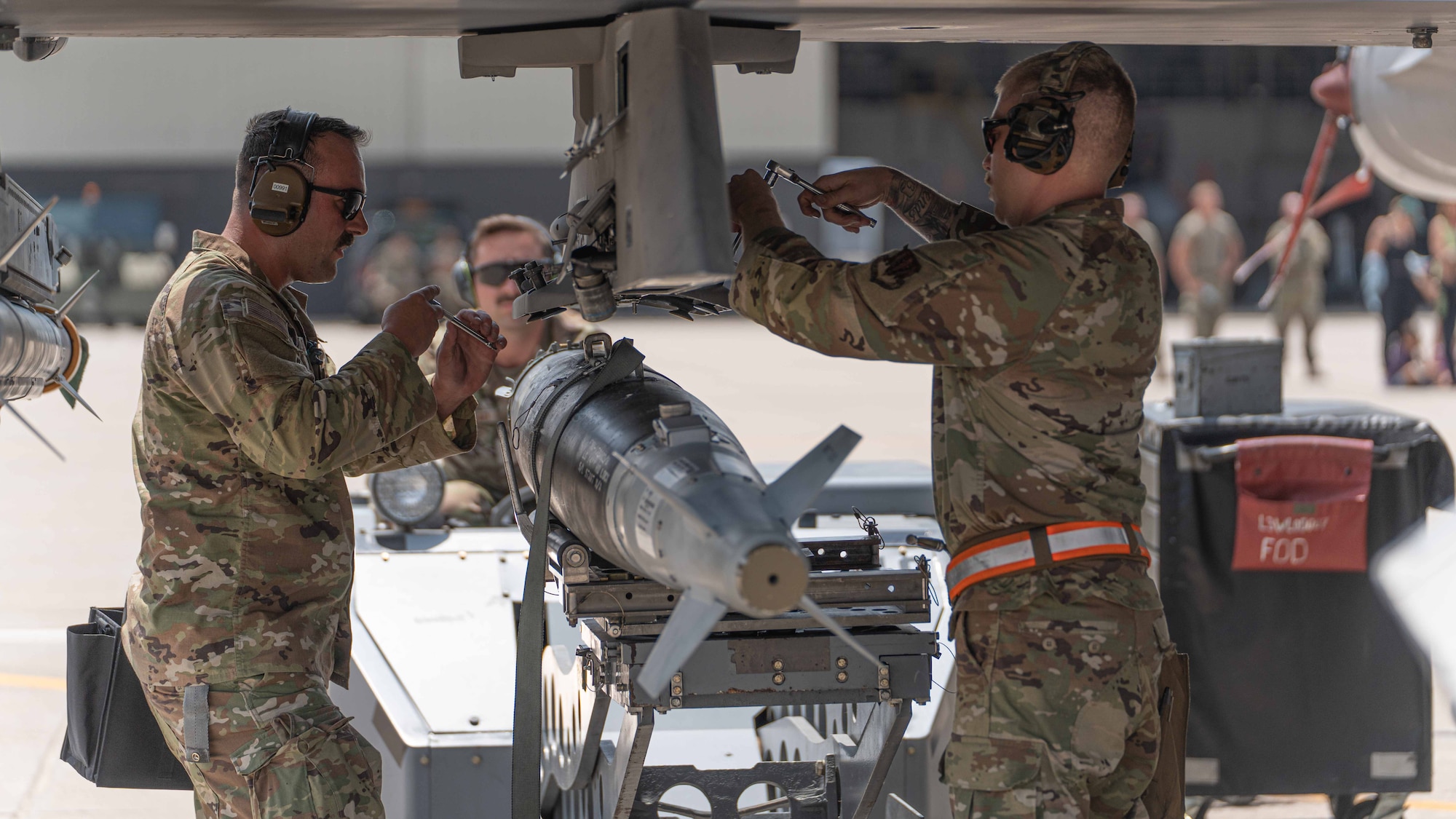 Guard Airmen equip an F-16 aircraft with munitions.