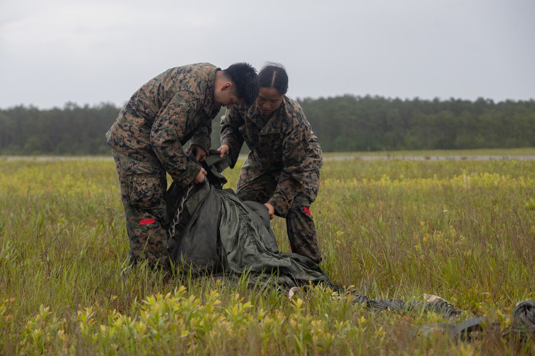 U.S Marine Corps 1st Lt. Linh Kolkowski, right, a logistics officer, and Lance Cpl. Agustin Florescanstaneda, left, an airborne and air delivery specialist, both with 2nd Distribution Support Battalion, 2nd Combat Logistics Regiment, 2nd Marine Logistics Group, packs a dropped parachute during air delivery operations on Marine Corps Base Camp Lejeune, North Carolina, June 11, 2025. Marines with 2nd Distribution Support Battalion and Marine Aerial Refueler Transport Squadron (VMGR) 252, 2nd Marine Aircraft Wing, conducted training using the new Joint Precision Air Delivery System, and heavy platforms, to ready units for upcoming integrated training exercises and weapons and tactics instructor courses.  Kolkowski is a native of New Jersey. Florescanstaneda is a native of Pennsylvania. (U.S. Marine Corps photo by Lance Cpl. Franco Lewis)