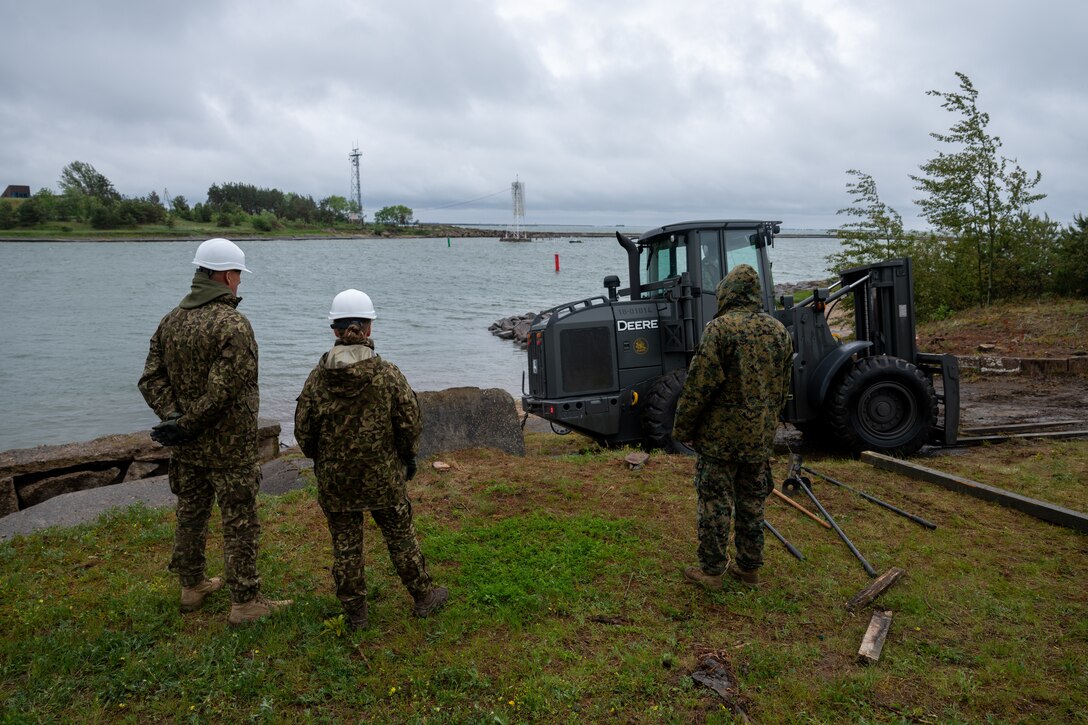 U.S. Marines with 8th Engineer Support Battalion, Combat Logistics Regiment 27, 2nd Marine Logistics Group, U.S. Navy Sailors assigned to Naval Construction Battalion (NCB) 14 and Latvian service members with Kurzemes 4th Brigade Engineering Unit clear debris using a forklift in preparation for a portable boat ramp installation during exercise Baltic Operations 2025 (BALTOPS 25) , June 9, 2025, in Liepaja, Latvia. BALTOPS 25, the premier maritime-focused exercise in the Baltic Region, provides a unique training opportunity to strengthen combined response capabilities critical to preserving freedom of navigation and security in the Baltic Sea. (U.S. Marine Corps photo by Sgt. Alyssa Chuluda)