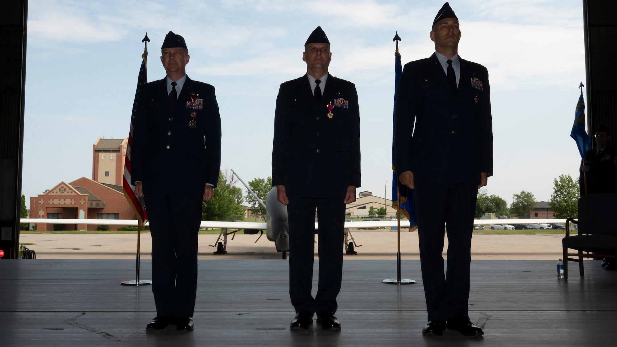 From left, Col. Tim Monroe, 319th Reconnaissance Wing commander, Col. Eric Steele, outgoing 319th Operations Group commander and Col. Brandon Cieloha, incoming 319th OG commander, stand at attention during the 319th OG change of command ceremony at Grand Forks Air Force Base, N.D., June 13, 2025.