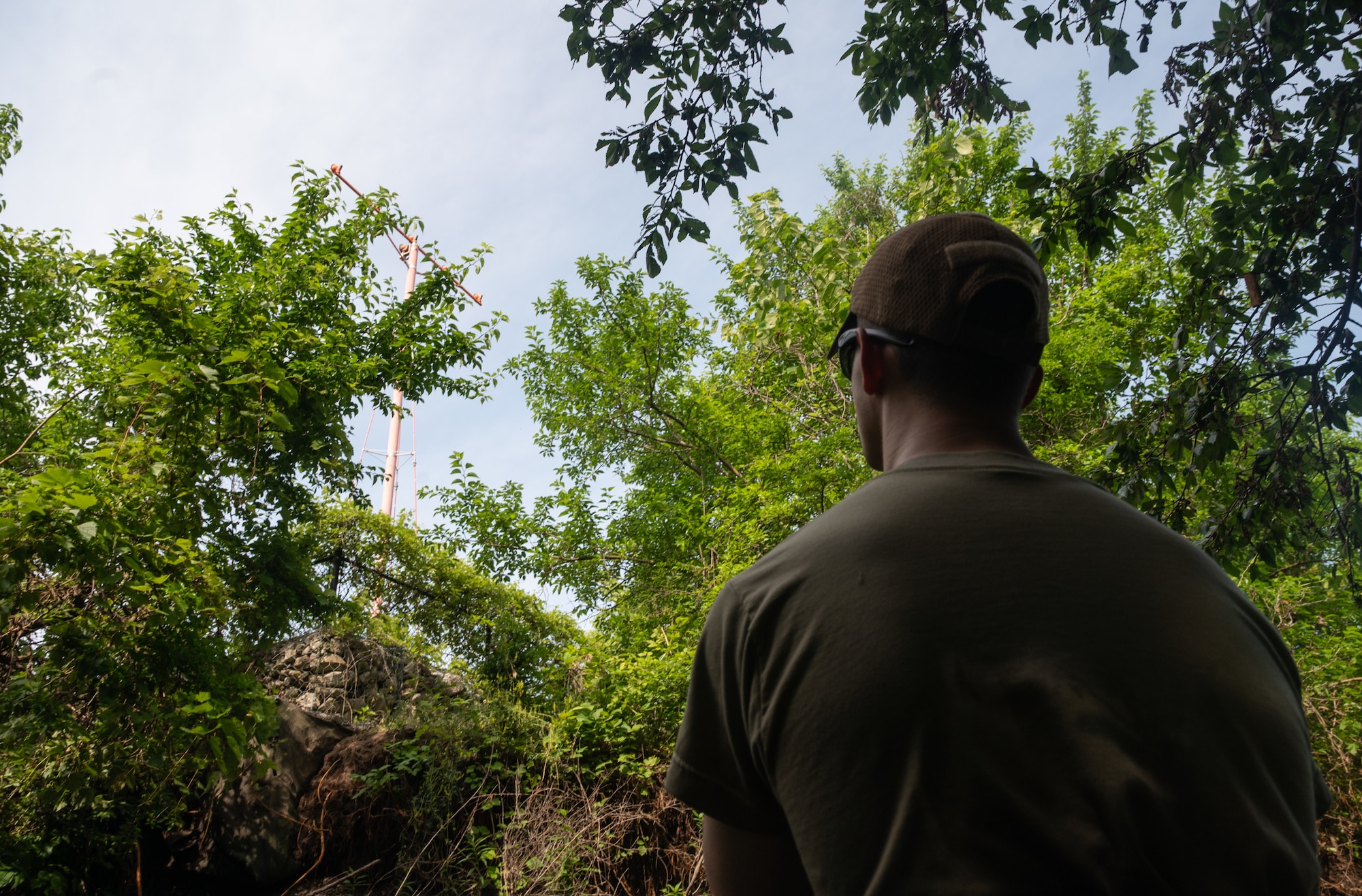 Senior Airman Skylar Ackley, 22nd Civil Engineer Squadron explosive ordnance disposal technician, surveys an approach light on the shoreline of a creek during a bank revetment project June 11, 2025, at McConnell Air Force Base, Kansas. Ackley volunteered to help with the project, which used trees to stabilize the bank and prevent erosion that was threatening the infrastructure of the approach lights on the southern tip of McConnell. (U.S. Air Force photo by Staff Sgt. Tryphena Mayhugh)