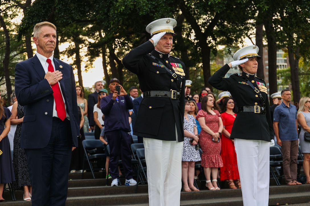 U.S. Congressman Robert Wittman, the representative of Virginia’s 1st Congressional District, left, U.S. Marine Corps Maj. Gen. William L. Bowers, commanding general of Marine Corps Recruiting Command, center, and U.S. Marine Corps Col. Carrie Batson, commanding officer of Marine Corps Barracks Washington, honor the colors during the U.S. National Anthem during a sunset parade ceremony at the U.S. Marine Corps War Memorial in Arlington, Va. June 10, 2025. The sunset parade is a symbolic representation of the Marine's professionalism, valor and dedication, paying tribute to those whose "uncommon valor was a common virtue" (U.S. Marine Corps photo by Lance Cpl. Brynn Bouchard)