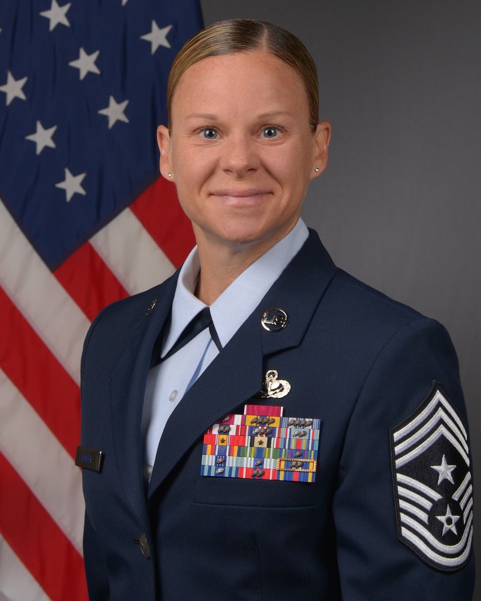 CMSgt Karissa L. Gunter poses for an official photo with an American flag in the background.