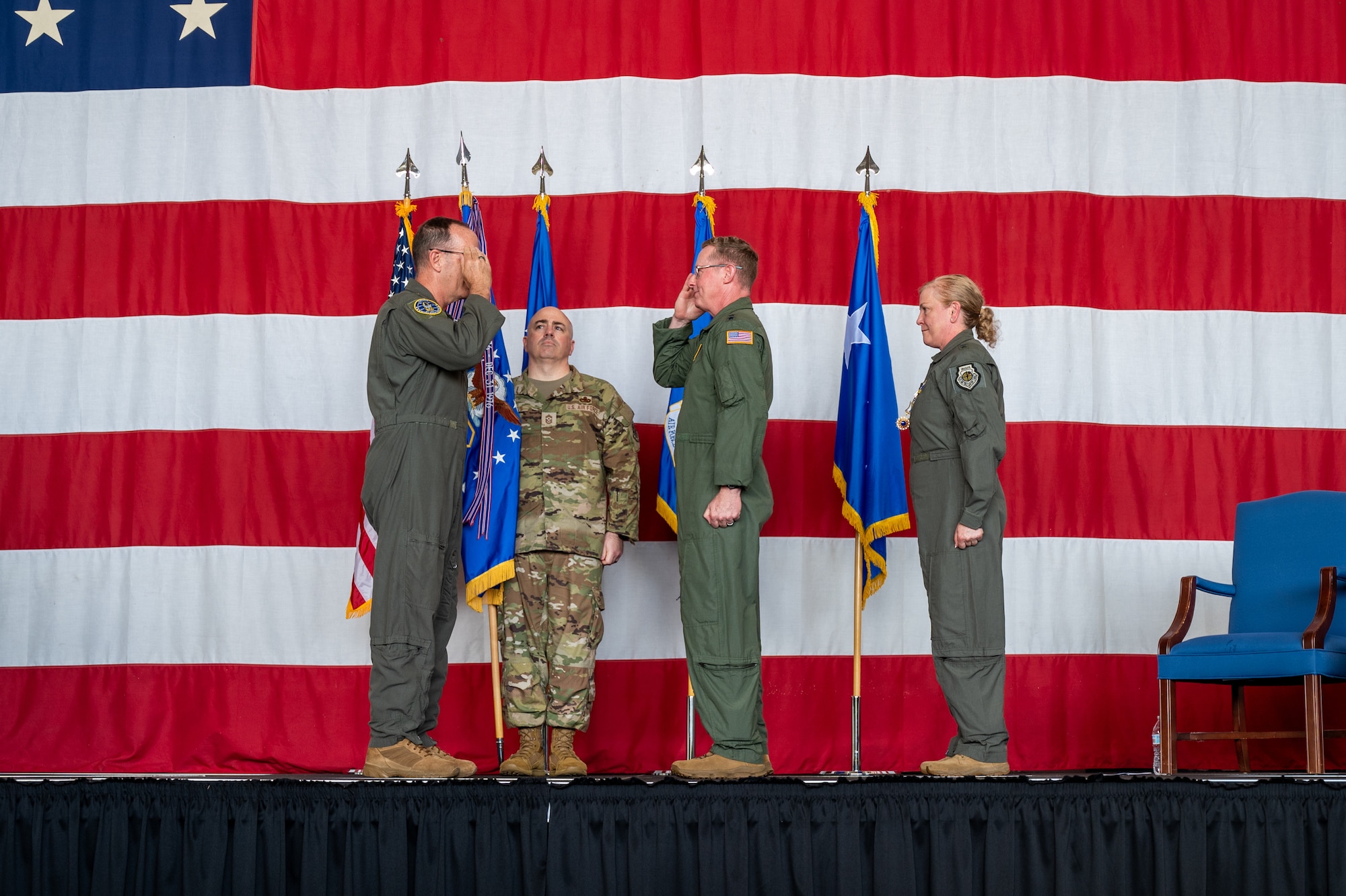 two men in military uniforms salute each other while standing on stage in front of flags