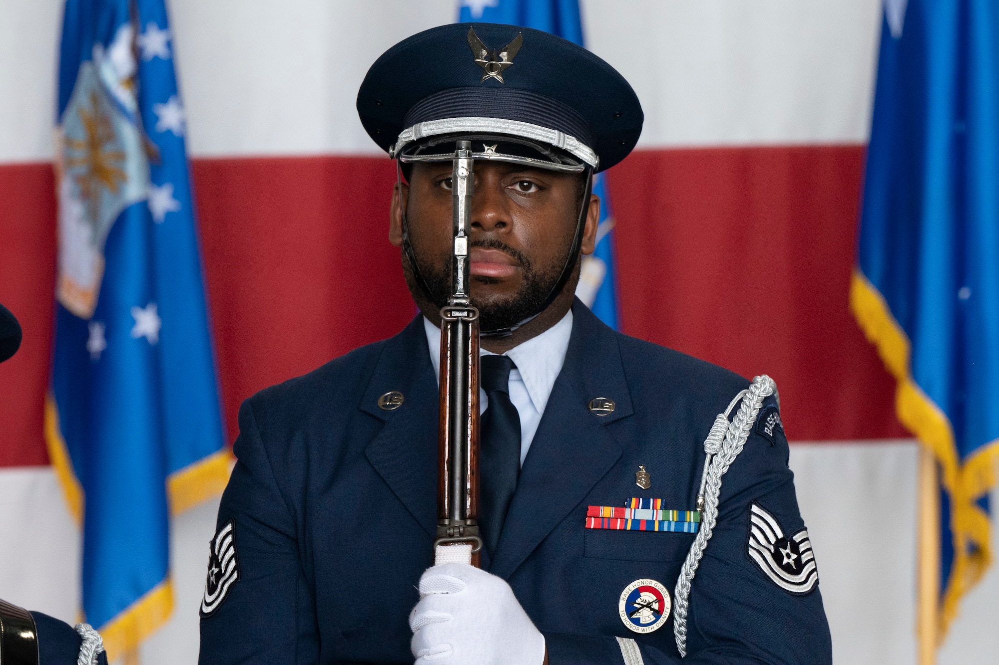 a man in a military uniform holds a rifle at the position of attention