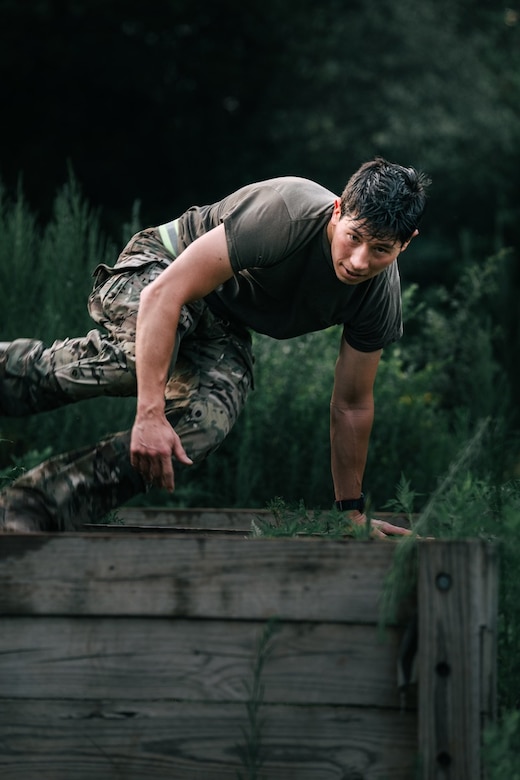 Man jumping over a wall in a military obstacle course.