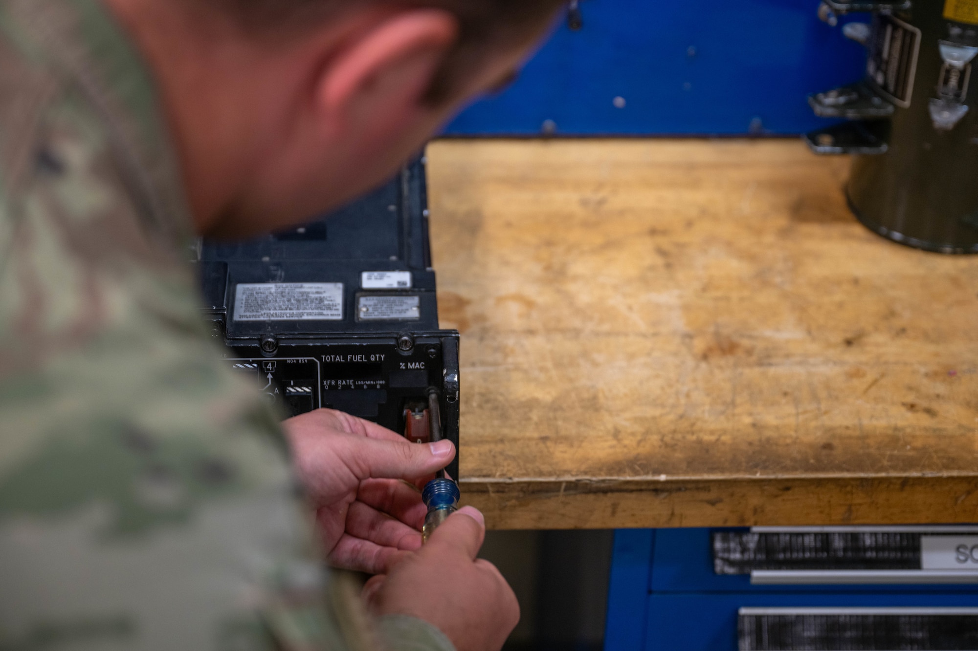 A man loosens a screw to repair an integrated fuel management panel.