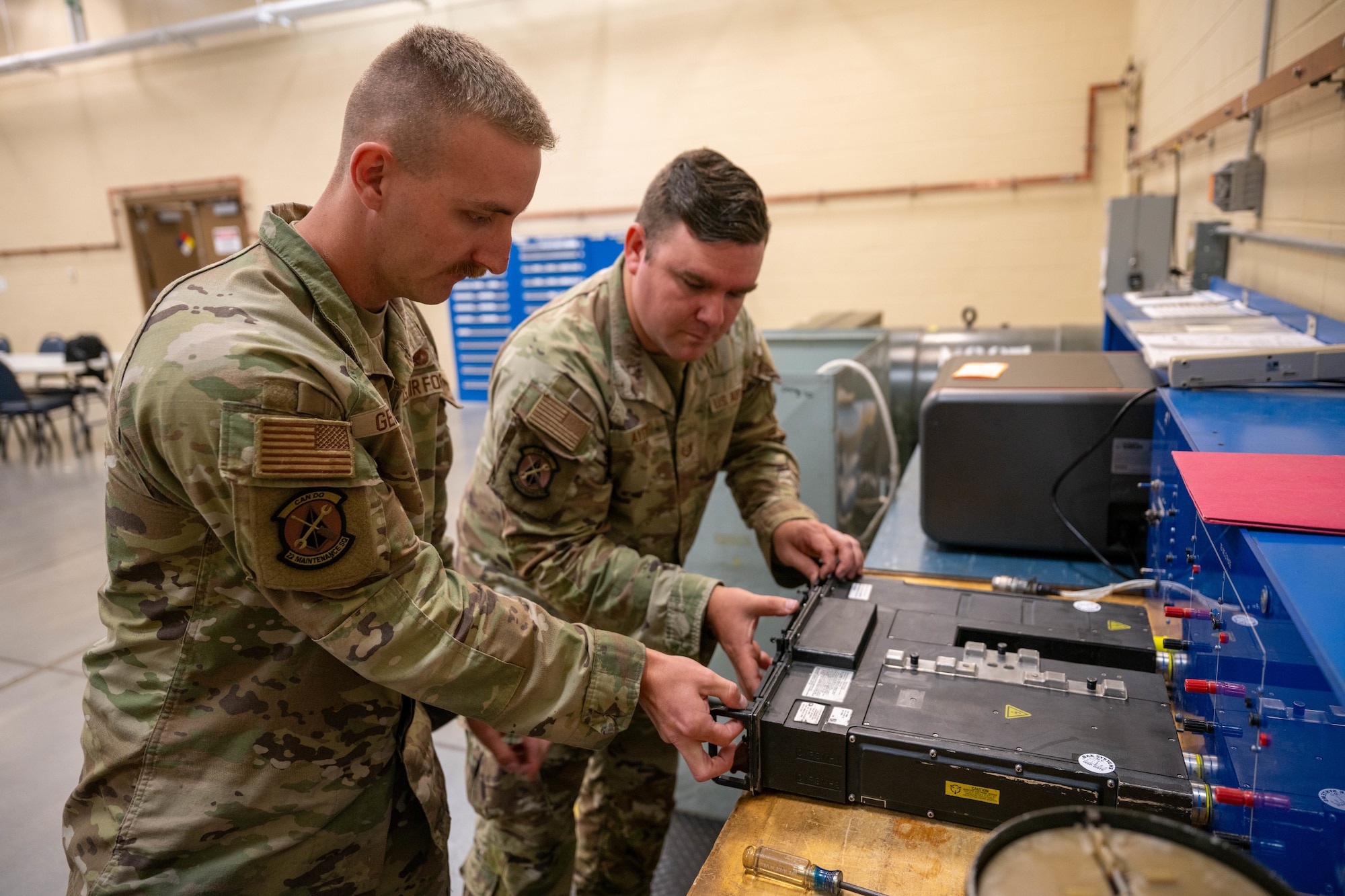 Two men open an integrated fuel management panel (IFMP) for repair.