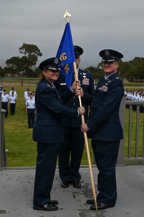 U.S. Air Force Col. Angelina Maguinness, 17th Training Wing commander, passes the guidon to Col. Jason Guyette, 517th Training Group commander, upon assuming command during the change of command ceremony on Soldier Field at Presidio of Monterey, California, June 12, 2025. The mission of the 517th Training Group is to train Airmen as linguists, develop airmen skills, and instill Air Force values. (U.S. Air Force photo by Staff Sergeant Nathan Call)