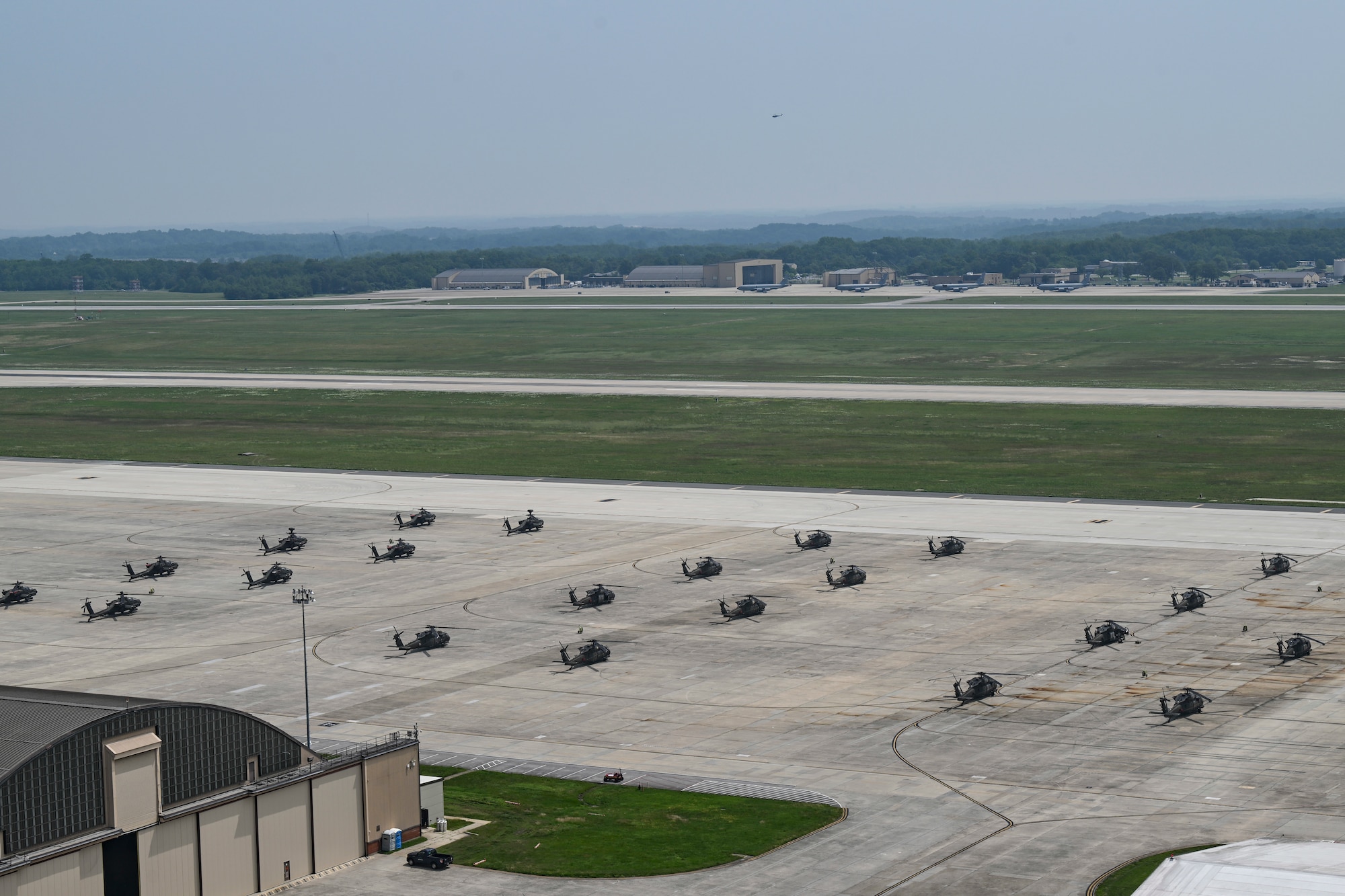 U.S. Army AH-64 Apache and UH-60 Black Hawk helicopters are parked on the flight line.