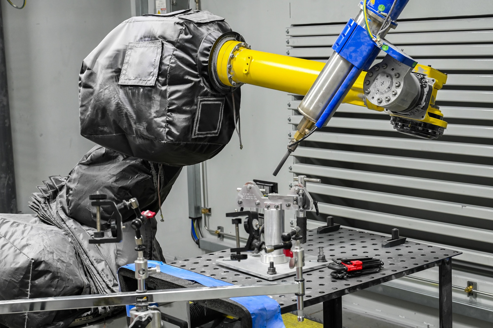 A robot arm equipped with the Centerline SST EPX spray system demonstrates its mechanical movement at ES3’s Cold Spray Repair Development Center, Abilene, Texas, May 20, 2025. The arm positions the spray system to apply metal powder precisely to a targeted surface. (U.S. Air Force photos by Airman 1st Class Adrien Tran)