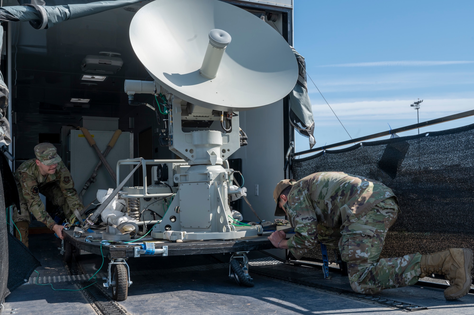 From left, U.S. Air Force Airman 1st Class Brayden Walling and Staff Sgt. Joao Gabriel, 92nd Communications Squadron radio frequency transmission technician and radio frequency operations noncommissioned officer in charge, moves a portable Global Aircrew Strategic Network Terminal system at Fairchild Air Force Base, Washington, June 2, 2025.  The global ASNT system uses extremely high frequency and advanced EHF waveforms to provide protected communication capabilities in operational environments. (U.S. Air Force photo by Airman 1st Class Samantha Thorn)