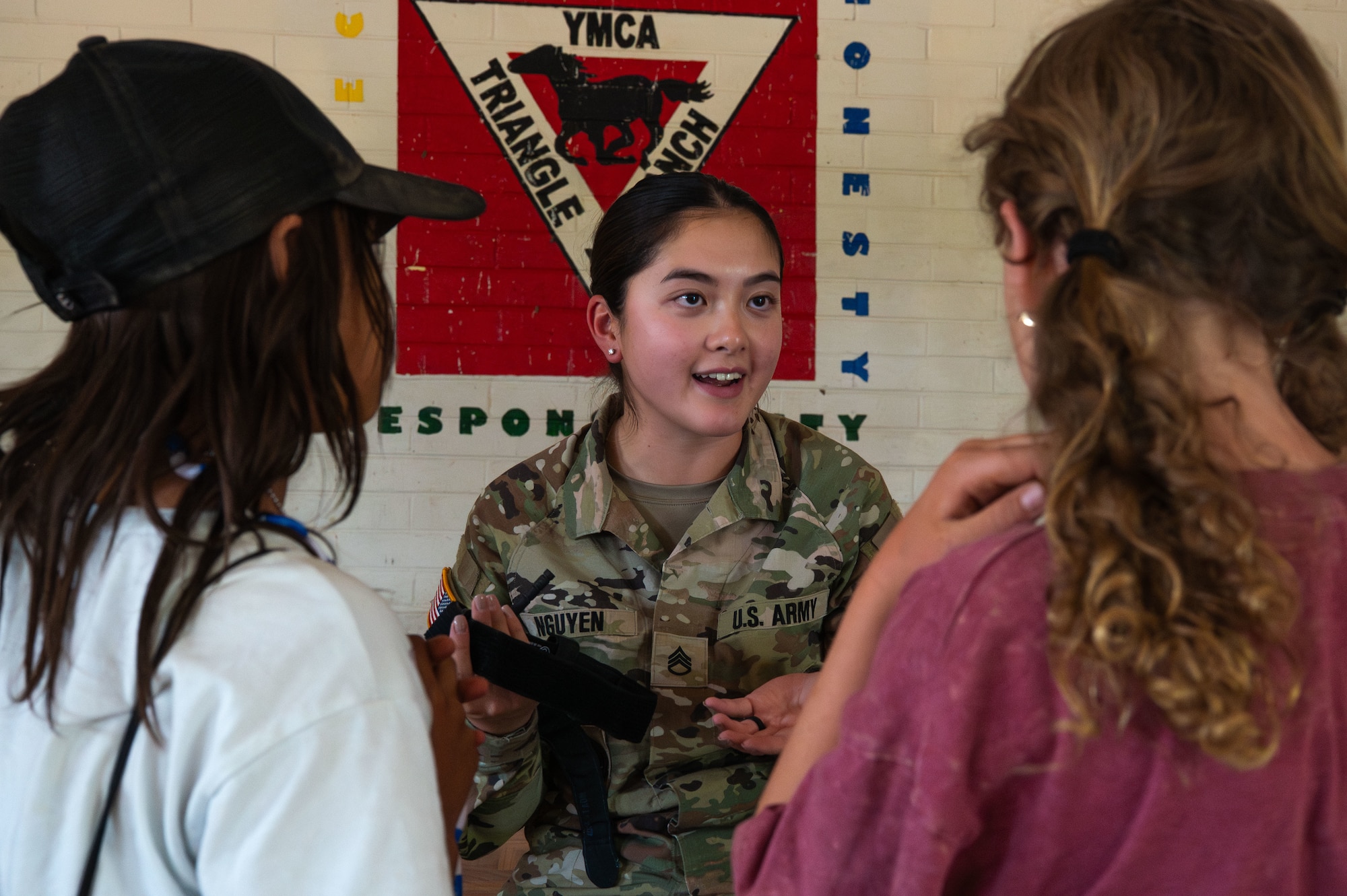 U.S. Army Staff Sgt. Kelly Nguyen, 2nd Battalion, 317th Regiment drill sergeant, shows YMCA Triangle Y Ranch campers how to use a tourniquet at Oracle, Arizona, June 12, 2025. Service members shared their knowledge and experiences while building connections with the local community. (U.S. Air Force photo by Senior Airman Jasmyne Bridgers-Matos)