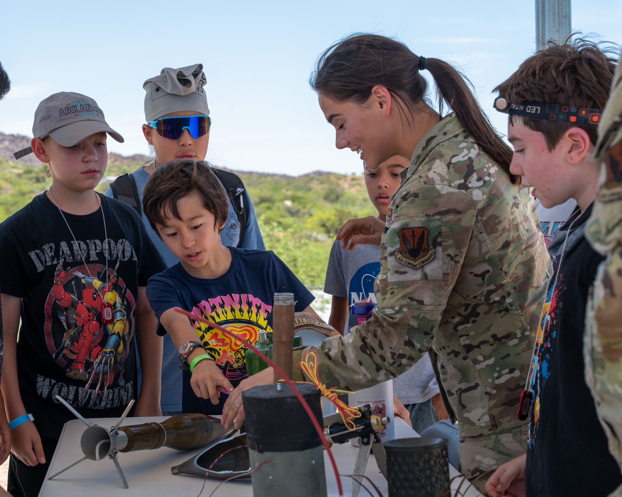 U.S. Air Force Airman 1st Class Gianna Baldizzi, 355th Civil Engineer Squadron explosive ordnance disposal technician, answers questions about different types of ordnance at Oracle, Arizona, June 12, 2025. Campers rotated through stations and activities to learn the roles Airmen play in supporting and sustaining the Air Force mission. (U.S. Air Force photo by Senior Airman Jasmyne Bridgers-Matos)