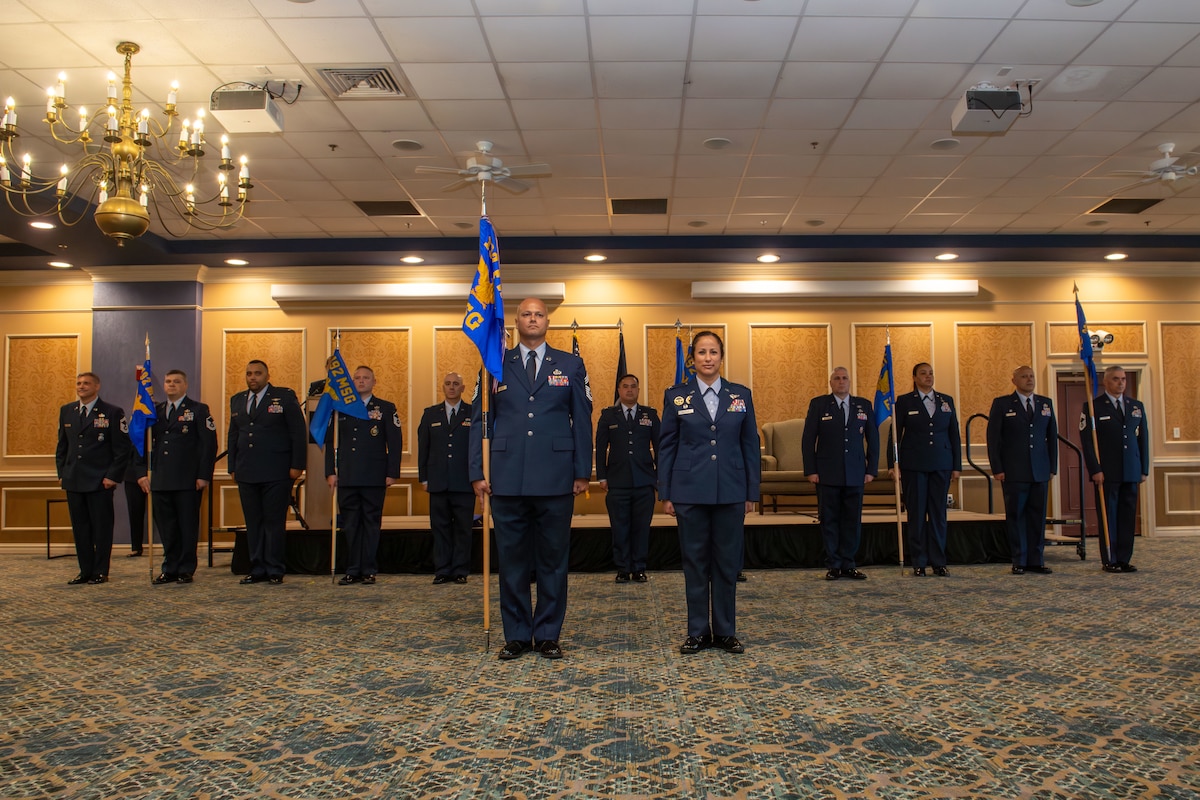 12 senior leaders from the 192nd Mission Support Group stand in a row with guidons for each flight and squadron with the group senior enlisted leader and commander in front