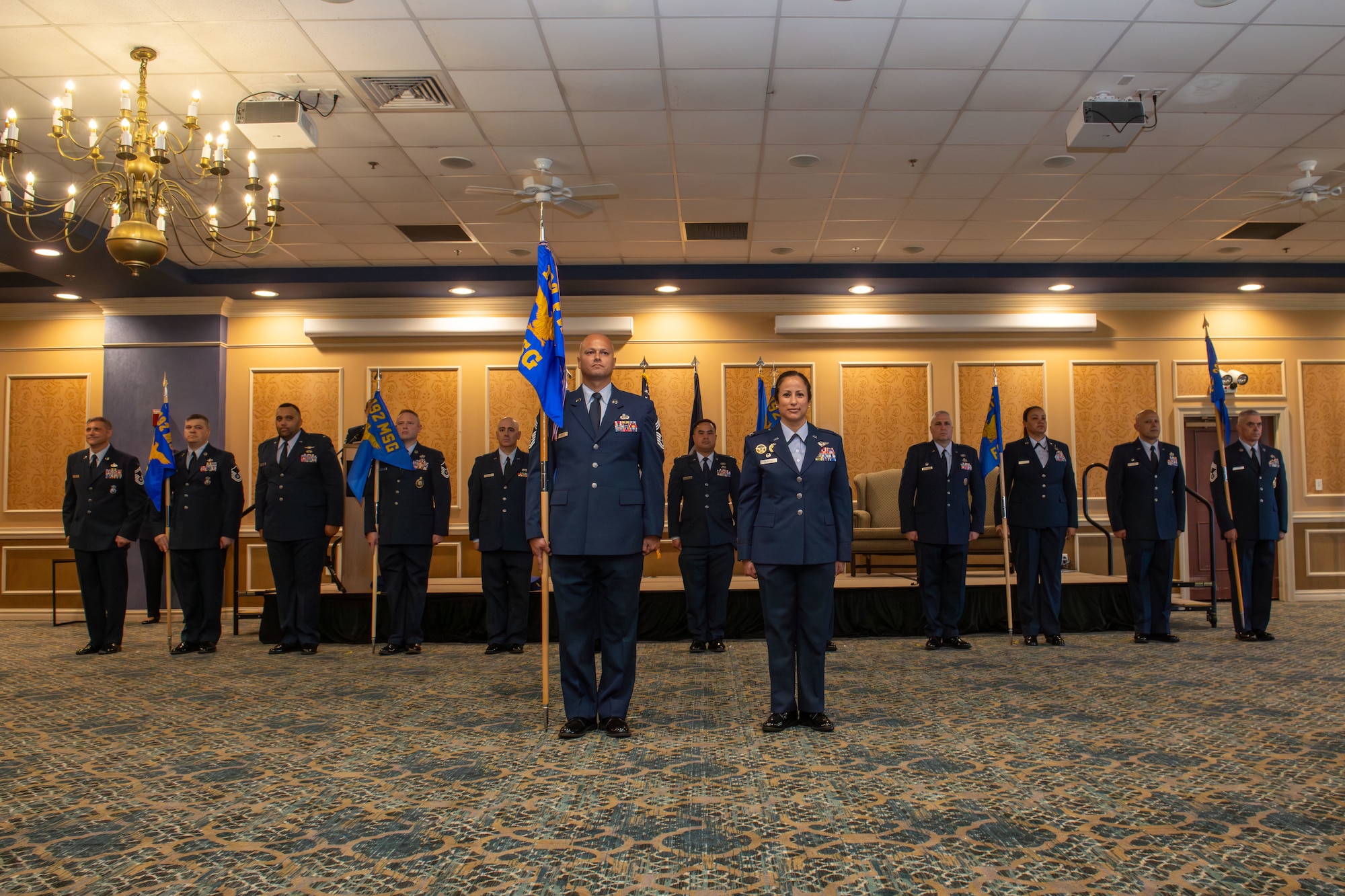 12 senior leaders from the 192nd Mission Support Group stand in a row with guidons for each flight and squadron with the group senior enlisted leader and commander in front