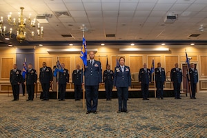 12 senior leaders from the 192nd Mission Support Group stand in a row with guidons for each flight and squadron with the group senior enlisted leader and commander in front