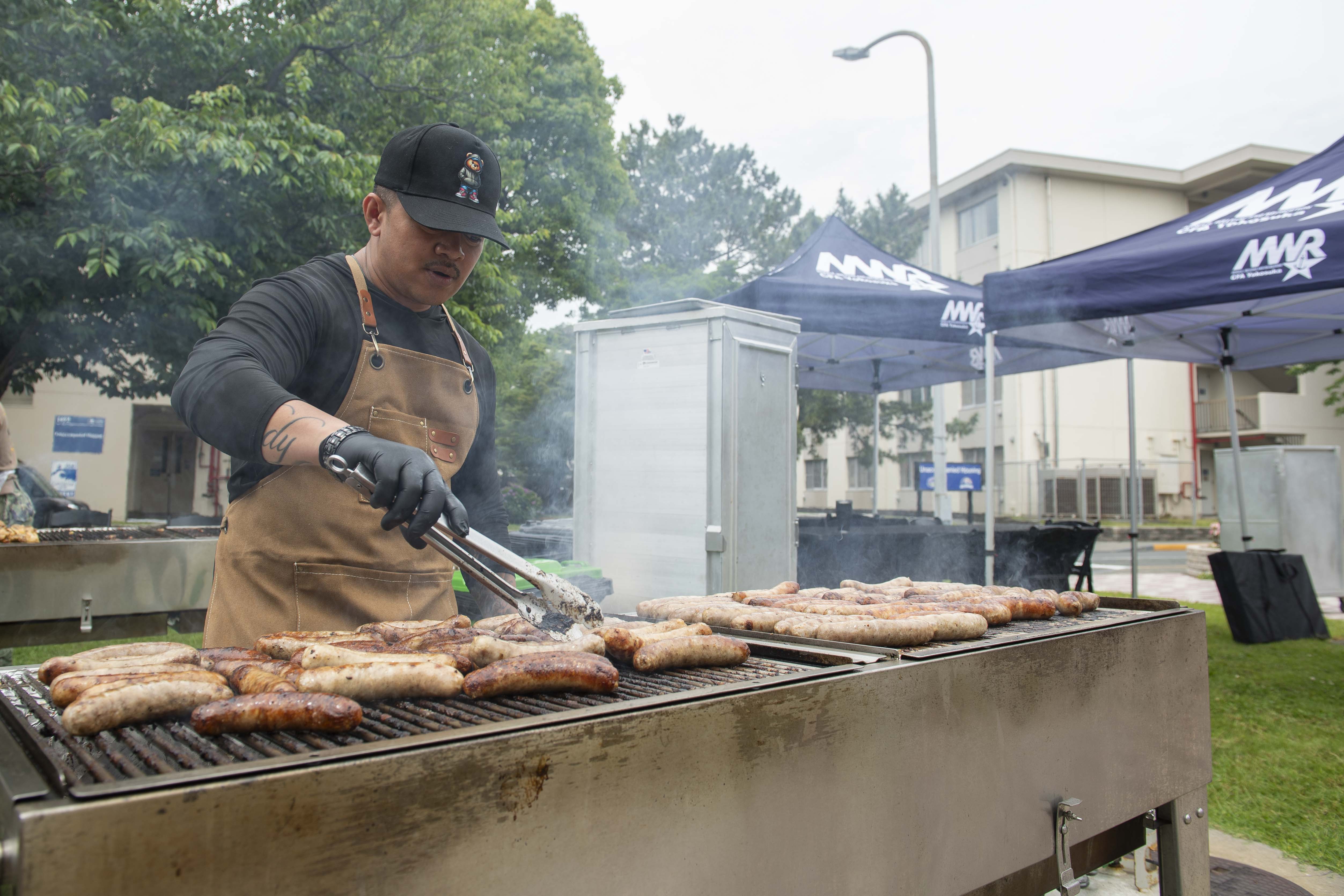 Senior Chief Culinary Specialist Rodolfo Elston grills sausages at the Commodore Matthew C. Perry General Mess Open Galley BBQ Event onboard Commander, Fleet Activities Yokosuka (CFAY) May 29, 2025.