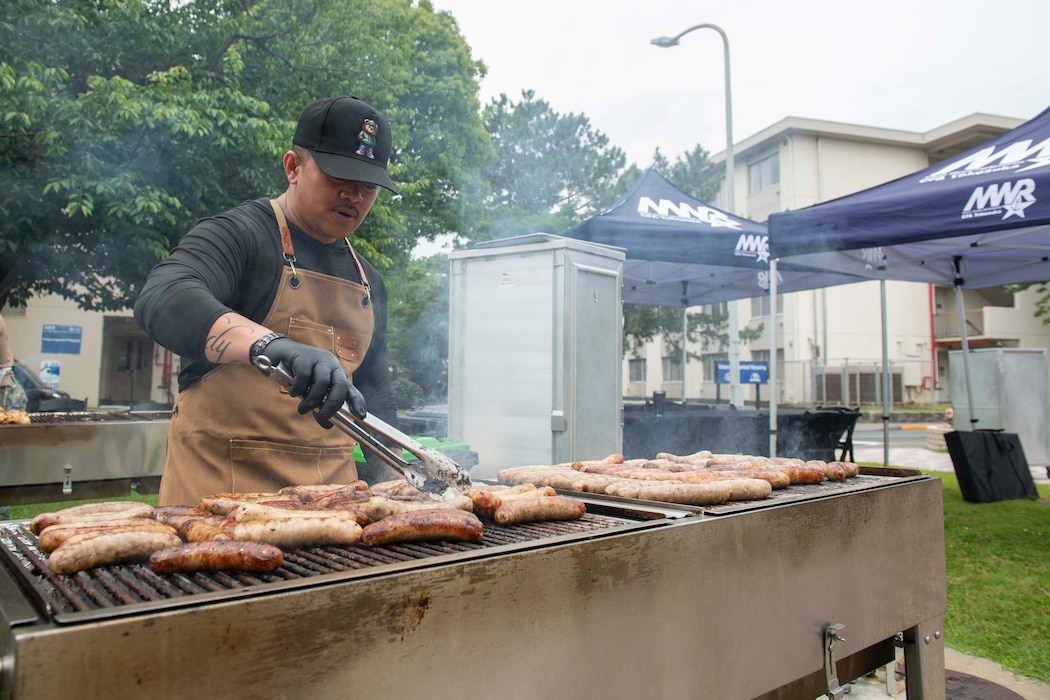 Senior Chief Culinary Specialist Rodolfo Elston grills sausages at the Commodore Matthew C. Perry General Mess Open Galley BBQ Event onboard Commander, Fleet Activities Yokosuka (CFAY) May 29, 2025.