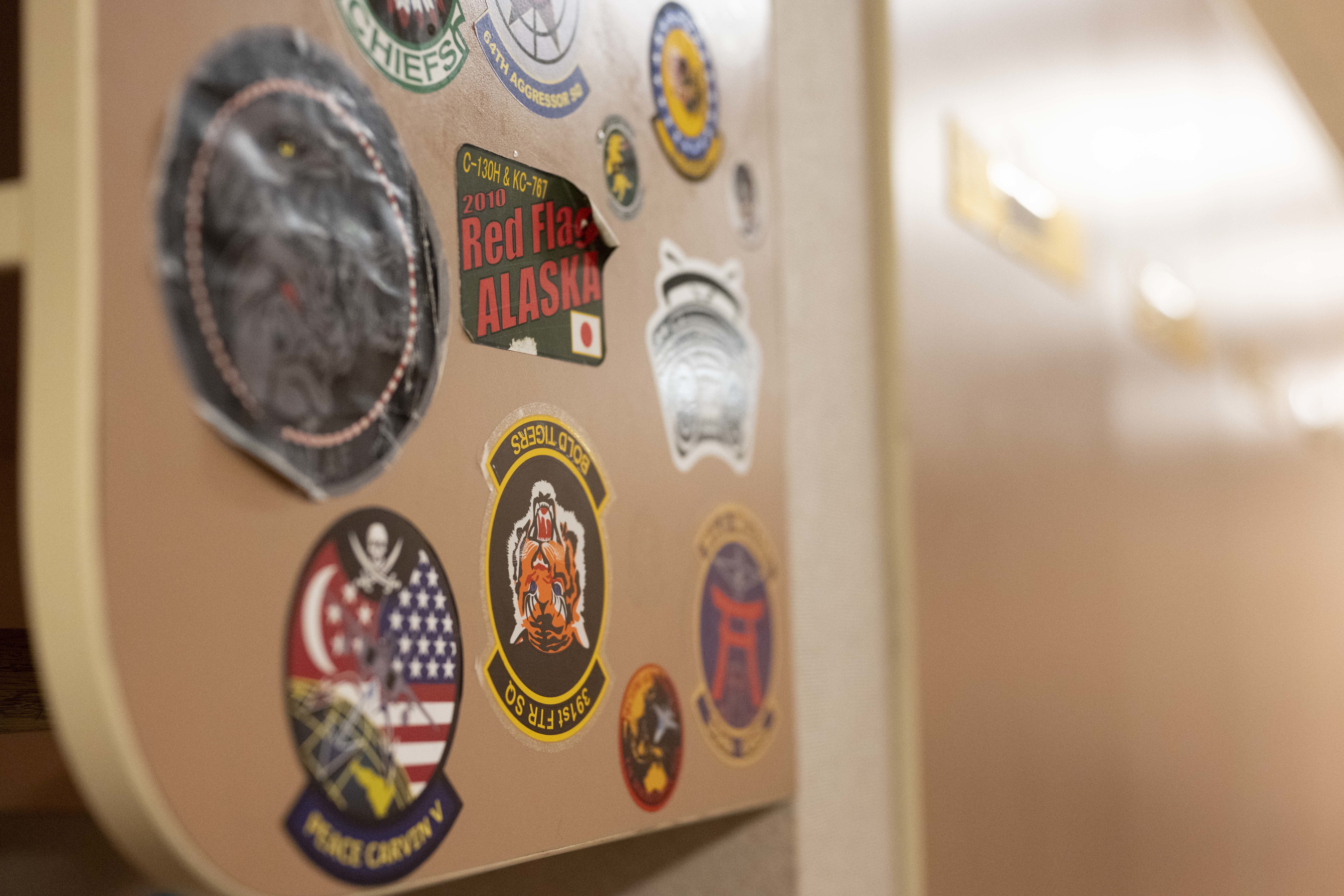 Stickers from units around the world who have supported Cope Thunder and Red Flag over the past 50 years lay on the walls of the Aircrew Flight Equipment office at the 353rd Combat Training Squadron on Eielson Air Force Base, Alaska, June 16, 2025. The collection reflects the legacy of units that have strengthened interoperability through Cope Thunder and Red Flag. (U.S. Air Force photo by Staff Sgt. Daniel Brosam)