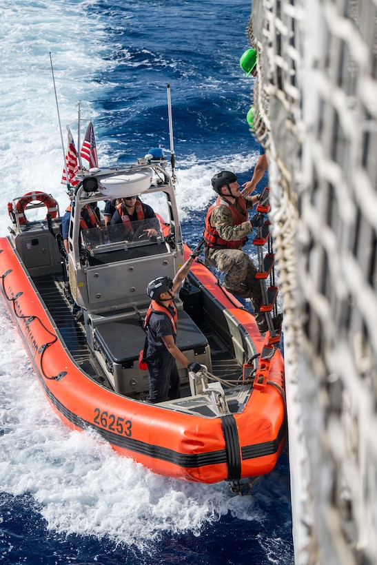 Cpl. Kenneth Lacy, a linguist for the U.S. Marine Corps transits from the fantail of the U.S. Coast Guard Cutter Harriet Lane (WMEC 903) to a 26-foot over-the-horizon small boat during a bilateral law enforcement operation between the U.S. Coast Guard and the Cook Island Ministry of Marine Resources June 9, 2025 in the Pacific Ocean. A unique instrument of security and stability, the U.S. Coast Guard bolsters maritime governance and supports peace and stability. (U.S. Coast Guard photo by Petty Officer 3rd Class Austin Wiley)