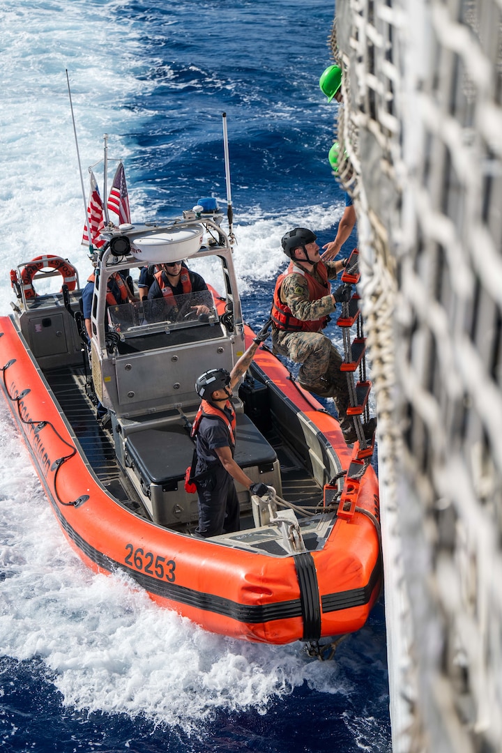 Cpl. Kenneth Lacy, a linguist for the U.S. Marine Corps transits from the fantail of the U.S. Coast Guard Cutter Harriet Lane (WMEC 903) to a 26-foot over-the-horizon small boat during a bilateral law enforcement operation between the U.S. Coast Guard and the Cook Island Ministry of Marine Resources June 9, 2025 in the Pacific Ocean. A unique instrument of security and stability, the U.S. Coast Guard bolsters maritime governance and supports peace and stability. (U.S. Coast Guard photo by Petty Officer 3rd Class Austin Wiley)