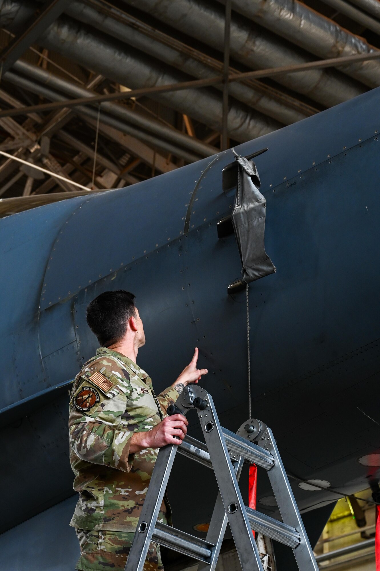 U.S. Air Force Tech. Sgt. Kevin Bratton, 7th Equipment Maintenance Squadron production expediter, points at a B-1B Lancer panel repaired using cold spray at Dyess Air Force Base, Texas, May 28, 2025. Cold spray is an innovative method for restoring B-1 outer panels, helping maintain mission readiness and combat lethality. (U.S. Air Force photos by Airman 1st Class Adrien Tran)