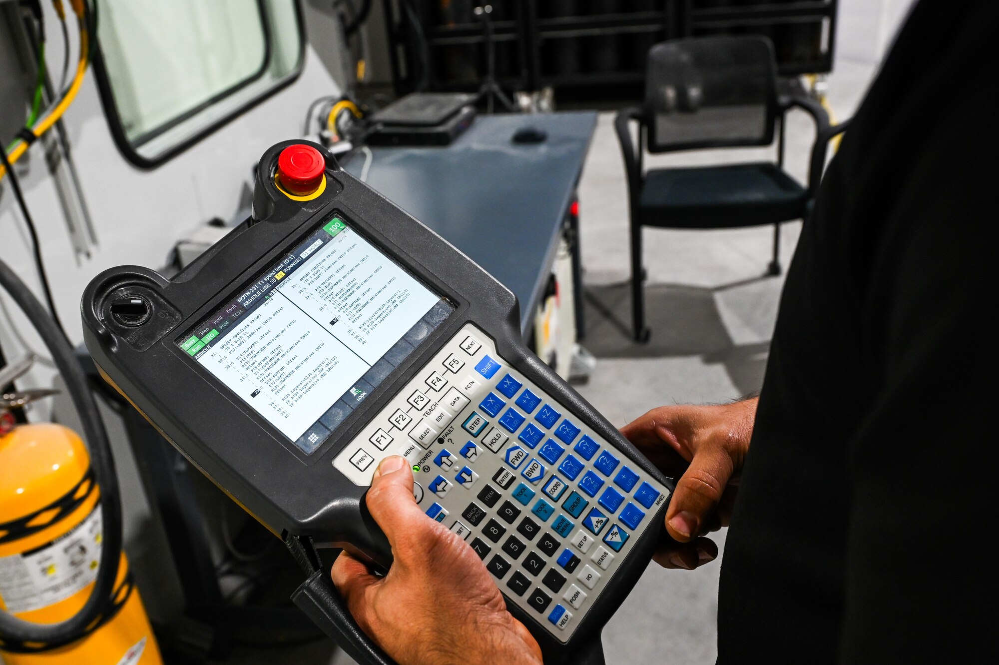 Marc Gilbert, ES3 Cold Spray Repair Development Center employee, operates a robot controller teach pendant at the facility in Abilene, Texas, May 20, 2025. The teach pendant is the primary method of programming and manually maneuvering the cold spray machine. (U.S. Air Force photos by Airman 1st Class Adrien Tran)