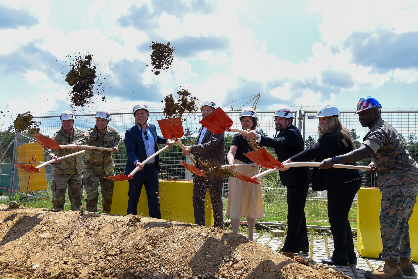 smiling people with shovels flinging dirt into the air