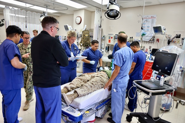 Emergency Department personnel at Naval Hospital Twentynine Palms conduct triage and initiate treatment on two role-playing Marines with simulated critical injuries during the Semper Durus 2025 regional training exercise, May 21. The casualties arrived via air medical evacuation following a notional explosion and friendly fire incident on Range 112, part of a mass casualty scenario coordinated with Marine Corps Air Ground Combat Center (MCAGCC) and other base tenants. After being transferred from the helipad by a corpsman and duty driver, the simulated patients were brought through the ambulance entrance, where medical teams activated the hospital’s Mass Casualty Protocol. The exercise provided a realistic test of interagency coordination, emergency medical response, and the hospital’s capacity to manage high-pressure incidents in real time (U.S. Navy photo by Christopher C. Jones, NHTP/NMRTC Twentynine Palms public affairs officer).