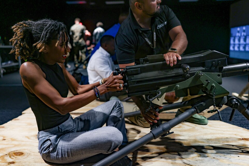 Jocelyn M. Mallette, left, secretary, North Carolina Department of Military and Veterans Affairs, fires a simulated Mark 19 grenade launcher during a distinguished visitor engagement on MCB Camp Lejeune, North Carolina, June 6, 2025. During her visit, Mallette toured the Warrior Athlete Readiness and Resilience Center, United Services Organization, Veterans Affairs intake site, and the Indoor Simulated Marksmanship Trainer. (U.S. Marine Corps photo by Lance Cpl. Alyssa J. DeCrane)