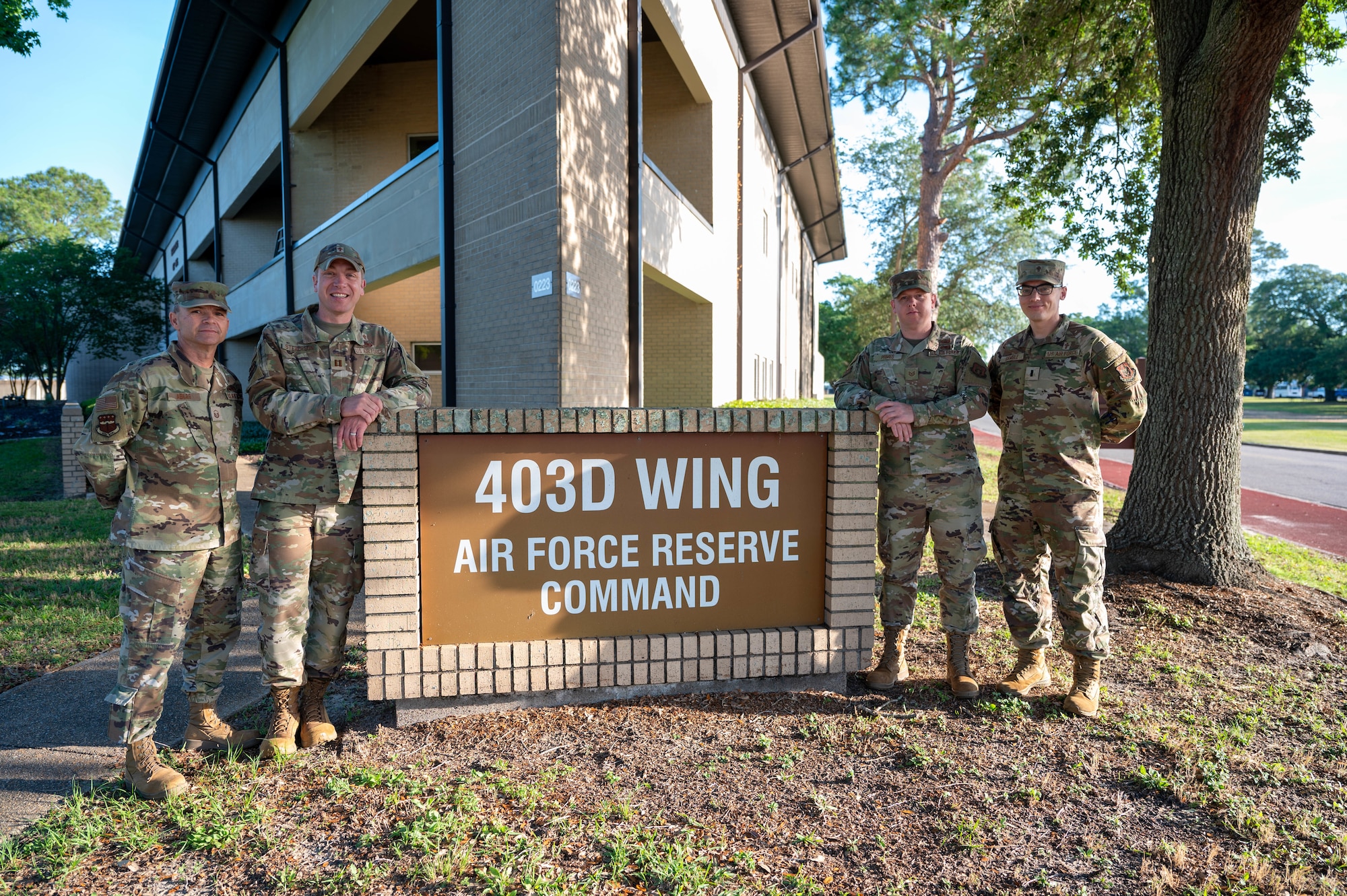 403rd Wing Religious Affairs Office members, stand in front of the wing headquarters sign.