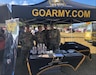 Soldiers pose for a picture standing under an Army canopy.