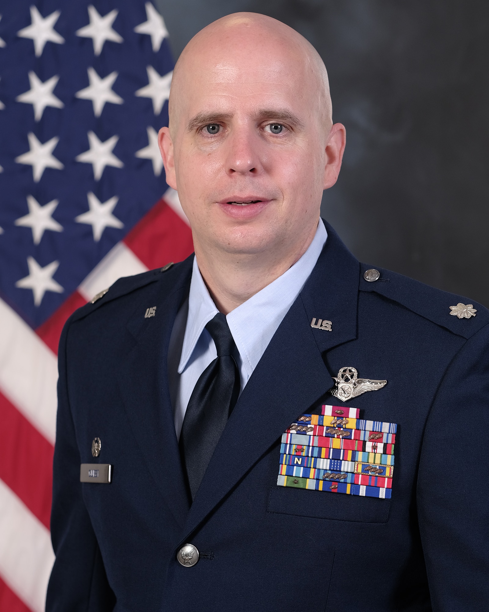 photo of uniformed US Airman standing in front of US flag