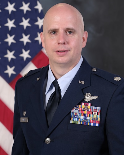 photo of uniformed US Airman standing in front of US flag
