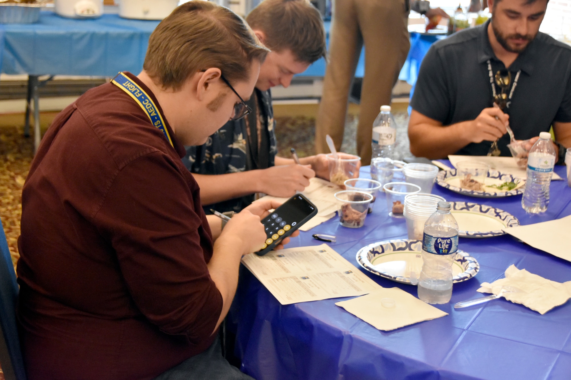 The judges tally their scores during the 804th Test Group BBQ Cookoff, June 6, 2025, at the Arnold Lakeside Complex on Arnold Air Force Base, Tenn. During the annual event, several members of the 804th Test Group team vie for the coveted large wooden fork, the trophy given to the cookoff victor, by preparing barbecue which is not only shared with colleagues across the test group, but also judged by several others on the 804TG team. (U.S. Air Force photo by Bradley Hicks)