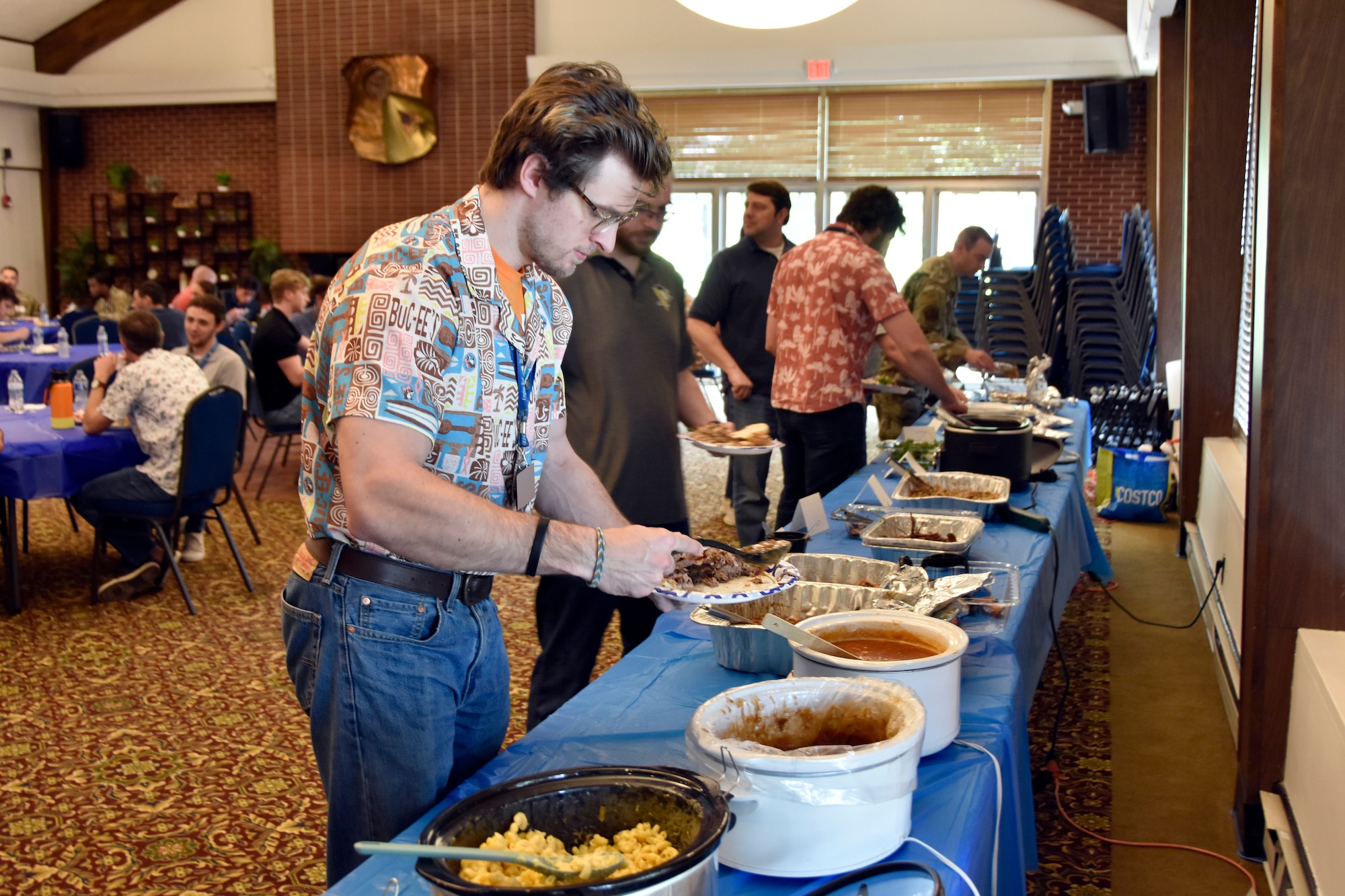 Maxwell Kreeb, test analyst in the 804th Test Group, samples some of the barbecue available during the 804th Test Group BBQ Cookoff, June 6, 2025, at the Arnold Lakeside Complex on Arnold Air Force Base, Tenn. During the annual event, several members of the 804th Test Group team vie for the coveted large wooden fork, the trophy given to the cookoff victor, by preparing barbecue which is not only shared with colleagues across the test group, but also judged by several others on the 804TG team. (U.S. Air Force photo by Bradley Hicks) (This image was altered by obscuring badges for security purposes)