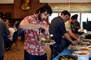Chase Wallen, test analyst in the 804th Test Group, adds some sauce to his dish during the 804th Test Group BBQ Cookoff, June 6, 2025, at the Arnold Lakeside Complex on Arnold Air Force Base, Tenn. During the annual event, several members of the 804th Test Group team vie for the coveted large wooden fork, the trophy given to the cookoff victor, by preparing barbecue which is not only shared with colleagues across the test group, but also judged by several others on the 804TG team. (U.S. Air Force photo by Bradley Hicks) (This image was altered by obscuring badges for security purposes)