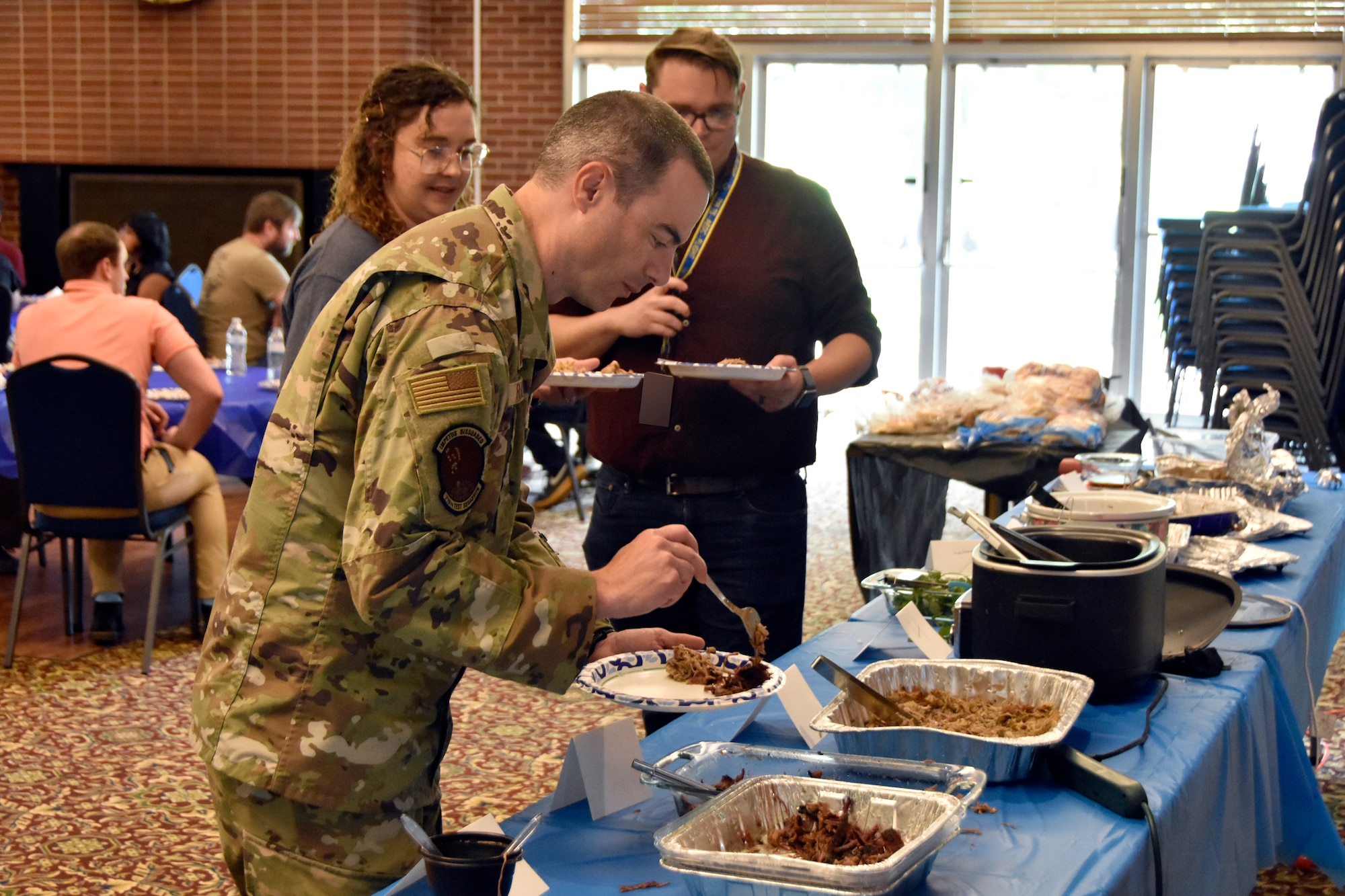 Lt. Col. Bryan Ralston, commander of the 719th Test Squadron at Hill Air Force Base, Utah, prepares a plate during the 804th Test Group BBQ Cookoff, June 6, 2025, at the Arnold Lakeside Complex on Arnold Air Force Base, Tenn. During the annual event, several members of the 804th Test Group team vie for the coveted large wooden fork, the trophy given to the cookoff victor, by preparing barbecue which is not only shared with colleagues across the test group, but also judged by several others on the 804TG team. (U.S. Air Force photo by Bradley Hicks) (This image was altered by obscuring badges for security purposes)