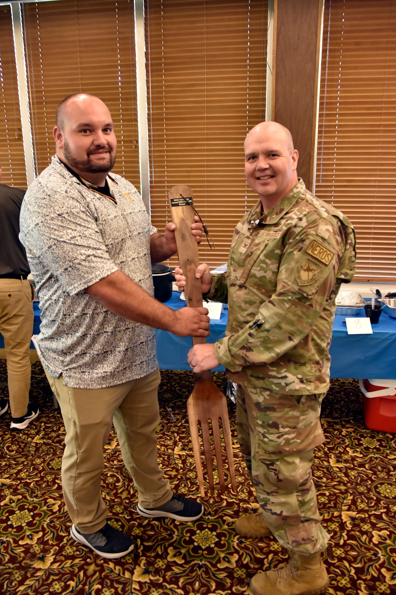 Will Garner, test manager in the 804th Test Group, left, receives the large wooden fork from 804TG Commander Col. Jason Vap for winning the 2025 804th Test Group BBQ Cookoff held June 6, 2025, at the Arnold Lakeside Complex on Arnold Air Force Base, Tenn. During annual event, several members of the 804TG team vie for the coveted fork, the trophy given to the cookoff victor, by preparing barbecue which is not only shared with colleagues across the test group, but also judged by several others on the 804TG team. (U.S. Air Force photo by Bradley Hicks)