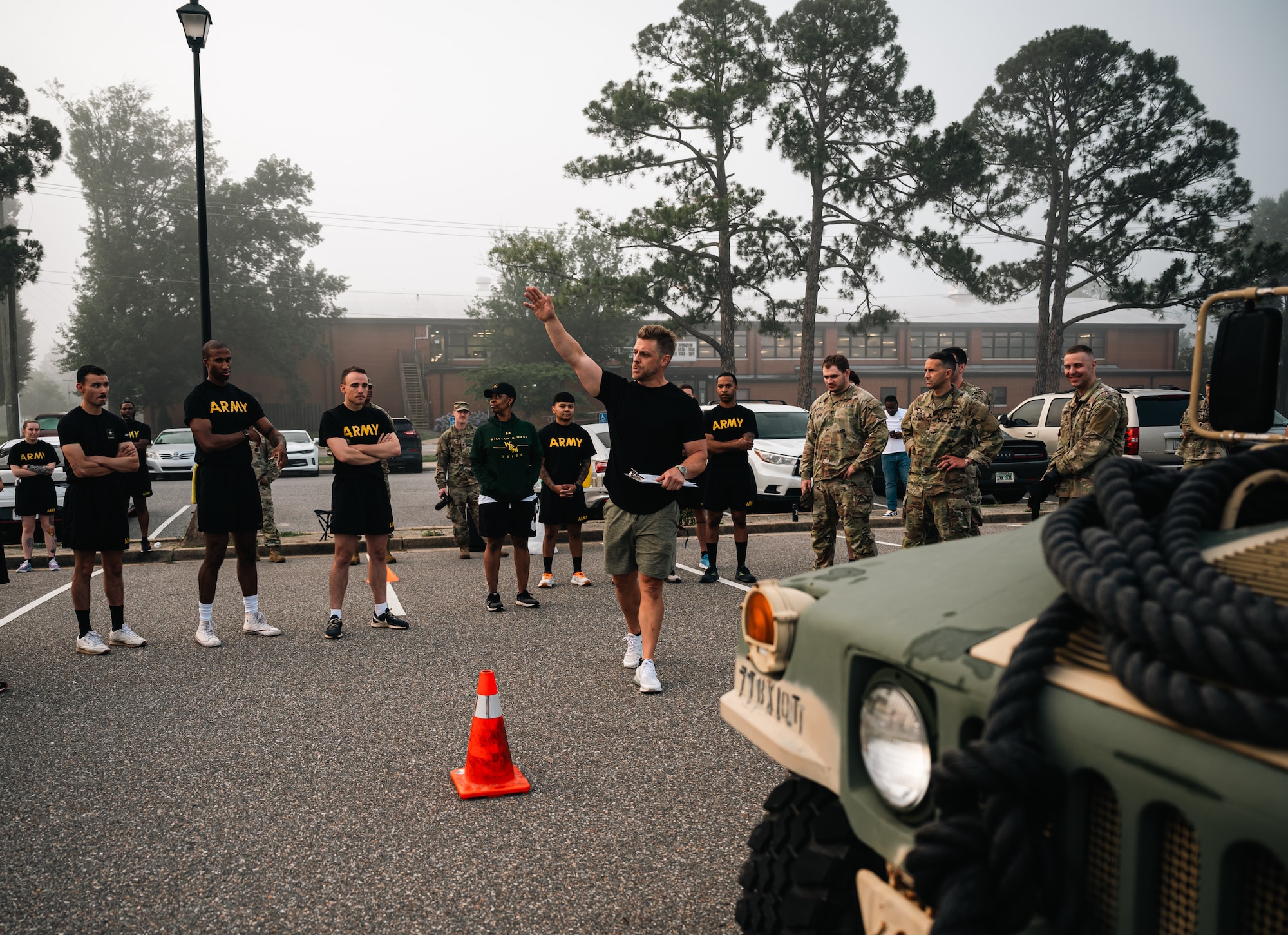Soldiers gather around a man in civilian clothes with his hand raised while outside