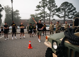 Soldiers gather around a man in civilian clothes with his hand raised while outside