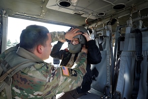 Kentucky National Guardsman placing his helmet on a young boy's head inside the Black Hawk helicopter