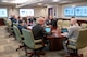A group of people sit around a table in a conference room.
