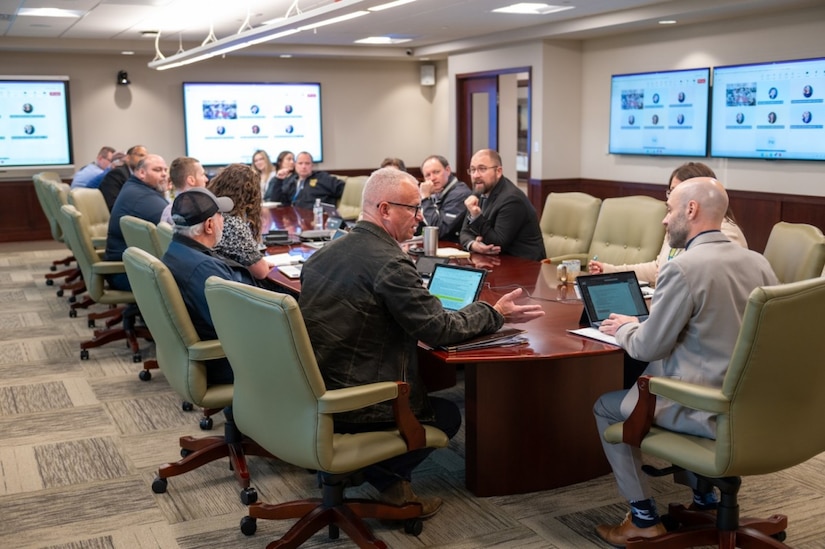 A group of people sit around a table in a conference room.