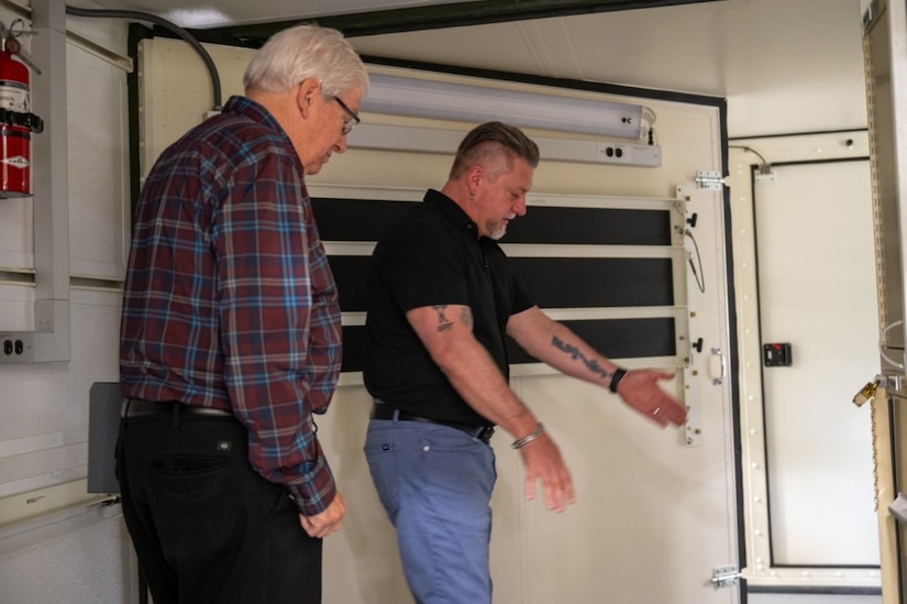 Two men standing in a military shelter.