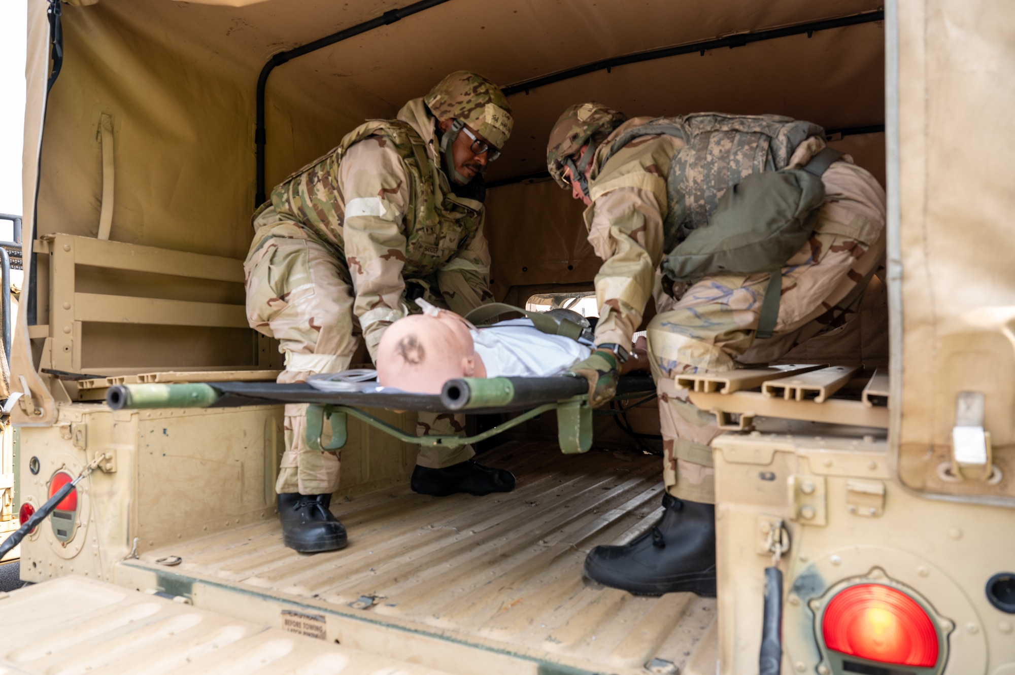 Airmen are dressed in full MOPP gear, loading simulated casualties into a military vehicle to simulate real life scenario of combat casualty care and evacuation.